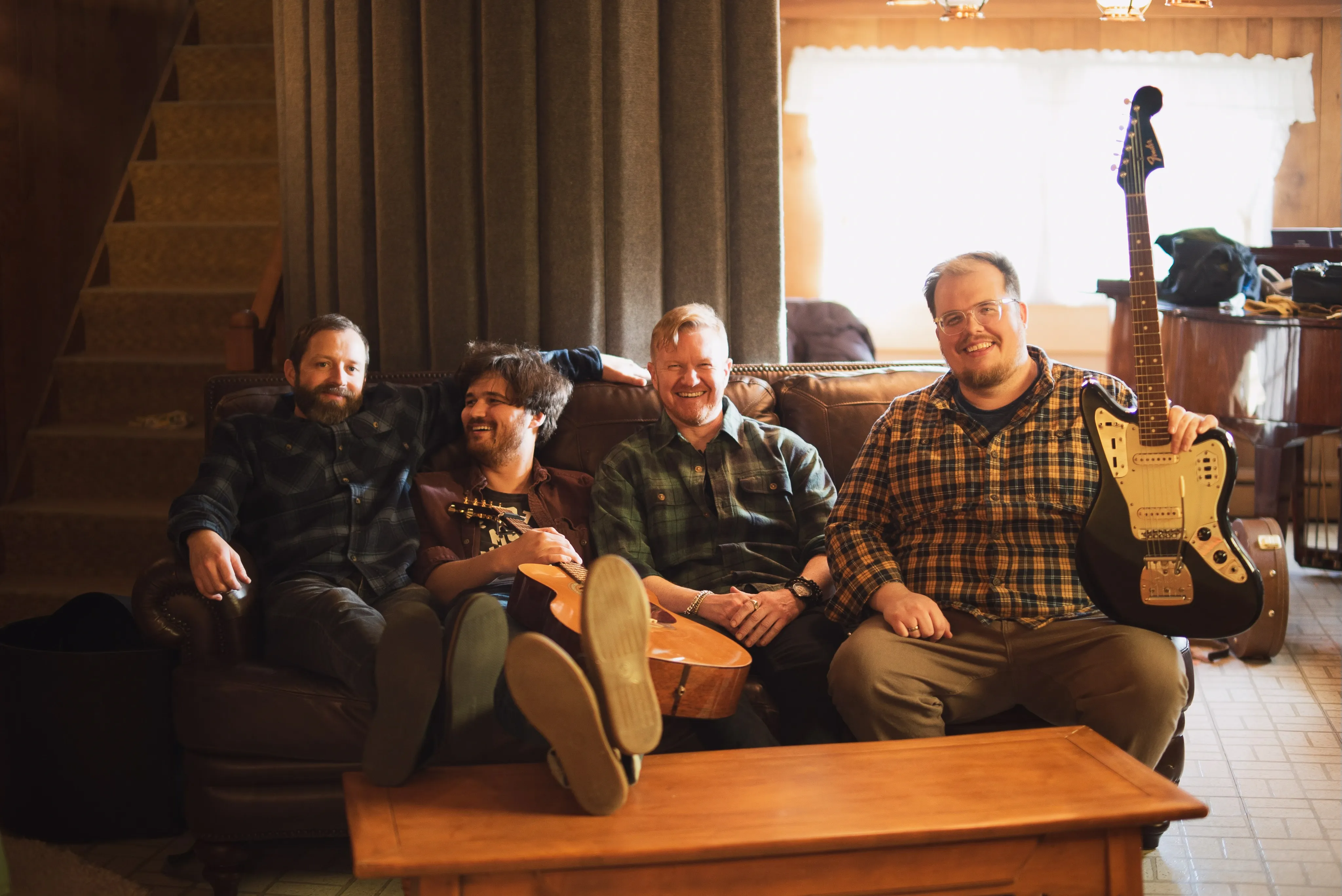 The four members of Barnweaver on a couch, instruments in hand